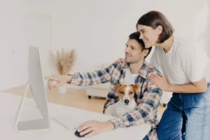 Happy husband points into monitor of computer, asks for useful advice in wife what better to buy