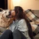 Kissing the dog. Woman is with golden retriever at home